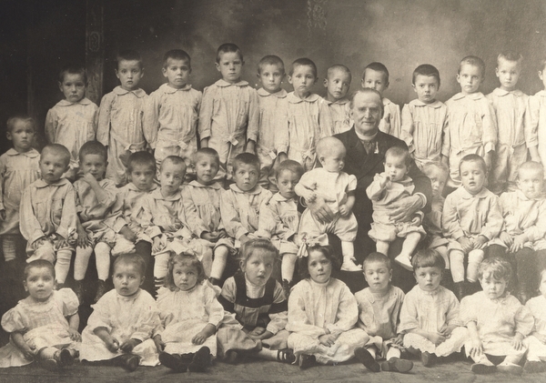 Father Baker sits with just a small portion of infants and children that he helped over the years of his service.